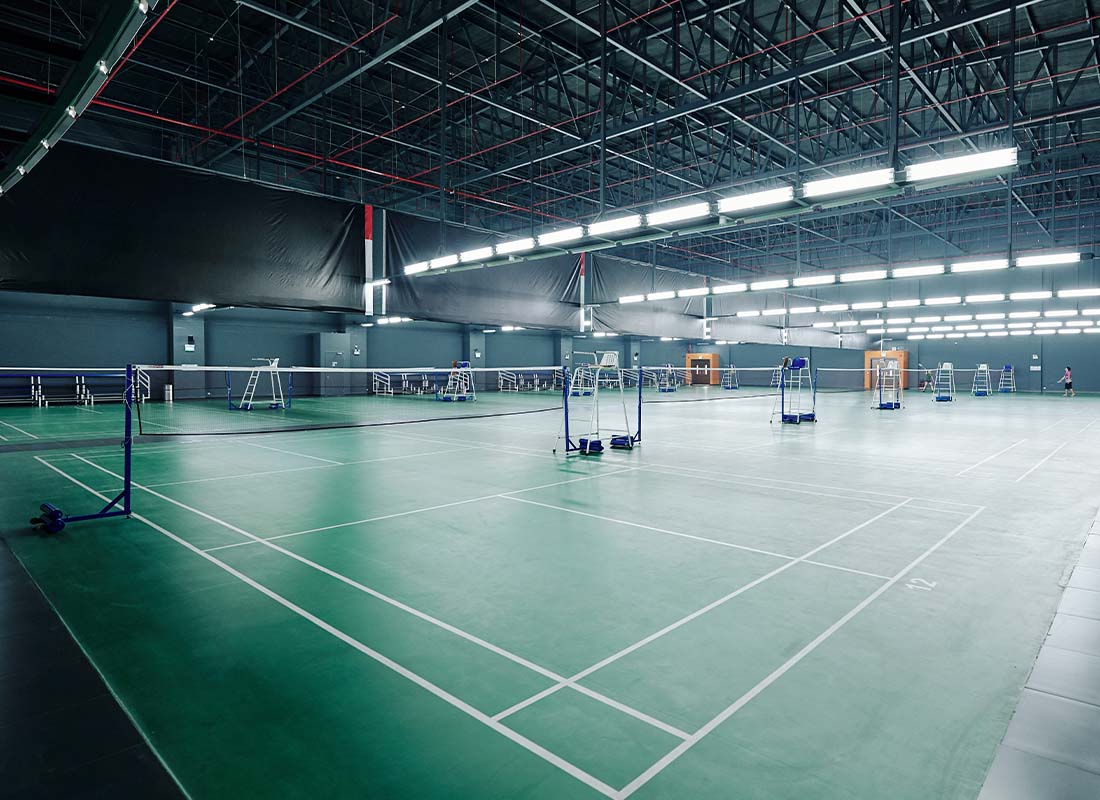 Sports Facility Insurance - Big Empty Gymnasium With Bright Lights and Courts for Playing Tennis and Badminton in a Health Club
